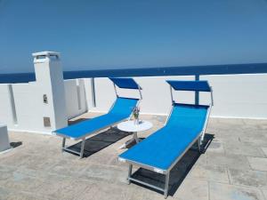 バーリにあるTerrazza marechiaroの青い椅子3脚と屋根の上のテーブル