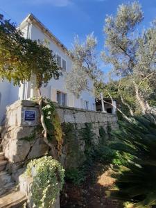 a white house with a stone wall and trees at Apartment Bianca Mljet mit Meerblick in Okuklje