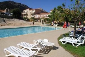 a group of lounge chairs next to a swimming pool at Les villas Maristella, résidence haut de gamme à deux pas de la mer in Aregno