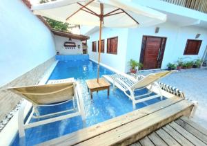 a swimming pool with two chairs and an umbrella at Casa Viana Trancoso in Trancoso