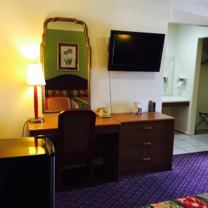 a hotel room with a desk and a tv at Hacienda Motel in Yuma