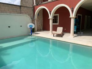 a swimming pool with a chair next to a building at Habitación con piscina en el centro de Mérida in Mérida
