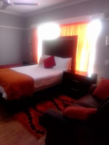 a bedroom with a large bed and a couch at Tara's Terrace Guest House in King Williamʼs Town
