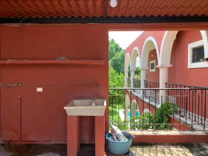 a red building with a sink and a balcony at Habitación con piscina en el centro de Mérida in Mérida