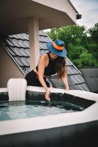 a woman in a hat standing next to a swimming pool at Vila harmony in Trmčare +12 photos