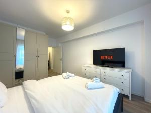 a bedroom with a white bed and a television at Lumial Mountain Nest in Braşov +20 photos