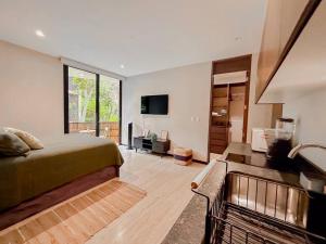 a bedroom with a bed and a living room with a tv at New Loft! Jungle Gym Best Pool in Tulum