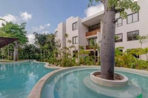 a swimming pool with a tree in front of a building at New Loft! Jungle Gym Best Pool in Tulum