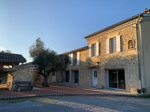 a stone building with a tree in front of it at Le mas des petites forêts in Chabeuil