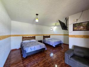 a room with two beds and a couch and a tv at Posada del camino in Tlahuelilpan