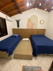 a bedroom with two beds and a wall with a painting at Casa em Juquehy flat 02 in São Sebastião