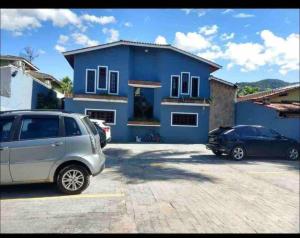 a blue house with two cars parked in a parking lot at Casa em Juquehy flat 02 in São Sebastião