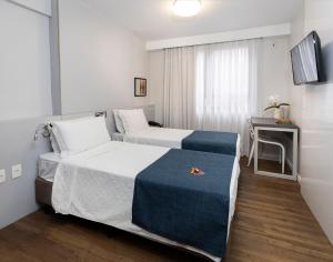 a hotel room with two beds and a desk at Tropikalya Prime Hotel in Balneário Camboriú +39 photos