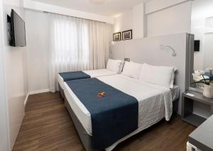 a bedroom with a large bed with a blue blanket at Tropikalya Prime Hotel in Balneário Camboriú