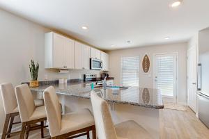 a kitchen with a large counter with chairs around it at Coastal Pines in Ocean Isle Beach +19 photos