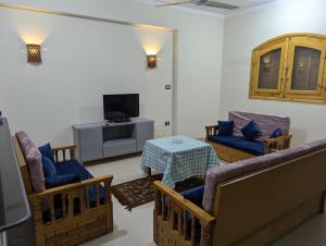 a living room with chairs and a table and a tv at Pharaohs Apartments in Luxor