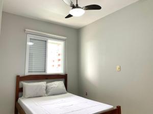 ein Schlafzimmer mit einem Bett mit Deckenventilator in der Unterkunft Apartamento no Centro ótima localização in Bertioga
