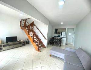 ein Wohnzimmer mit Treppe und Couch in der Unterkunft Apartamento no Centro ótima localização in Bertioga