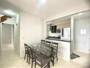 eine Küche und ein Esszimmer mit einem Glastisch und Stühlen in der Unterkunft Apartamento no Centro ótima localização in Bertioga + 16 Fotos