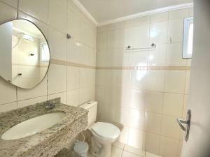 ein Badezimmer mit Waschbecken, Toilette und Spiegel in der Unterkunft Apartamento no Centro ótima localização in Bertioga