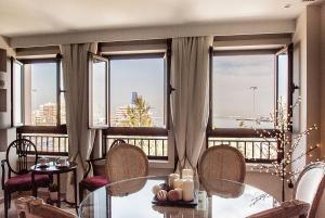 uma sala de estar com uma mesa, cadeiras e janelas em Apartamento Vistabella em Cádiz