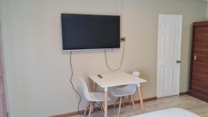 a room with a table and a tv on a wall at Hostal Bambu in Huertos Familiares +17 photos