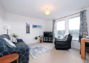 una sala de estar con un sofá y una silla en Harbour view 2 weeks City centre Apt, en Aberdeen