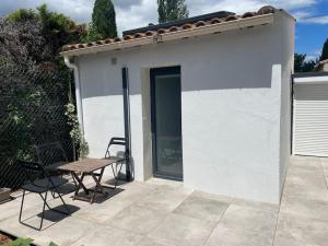 un piccolo edificio bianco con tavolo e sedia di Petit studio au fond du jardin a Saint-André-de-Sangonis