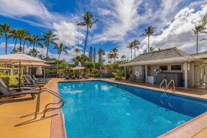 a pool with chairs and umbrellas and palm trees at Alii Kai II 10A in Princeville