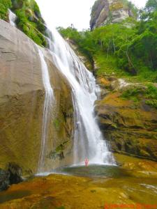 a person standing in a pool in front of a waterfall at 11Suites casa Suite #5 in Caraguatatuba +4 photos