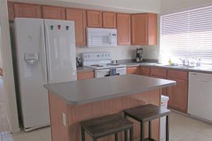 a kitchen with a white refrigerator and a counter with stools at Cozy house near I-10 with pool heater, hot tub, BBQ in Goodyear