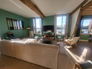 a living room with a couch and a tv at Le Cœur du Bien-être - Gîte grande capacité - 6 chambres - Superbe emplacement - Vue Seine - Décoration soignée - Coin touristique in Les Andelys