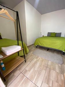 a bedroom with a green bed and a wooden floor at Terrazas Guest House-Hostal in Suchitoto