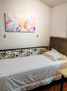 a bed in a room with a painting on the wall at Sobradinho Completo a 150 m da Praia in São Lourenço do Sul +9 photos