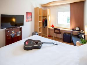 um quarto de hotel com uma guitarra numa cama em Ibis Hotel Plzeň em Plzeň