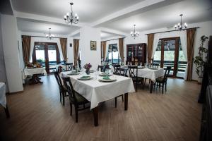 a dining room with white tables and chairs and windows at Hanul BRĂTEANU in Suceava