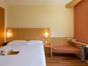 a bedroom with a large white bed and a bench at ibis Stuttgart Airport Messe in Leinfelden-Echterdingen