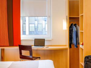 a bedroom with a desk with a laptop and a window at ibis Stuttgart Airport Messe in Leinfelden-Echterdingen