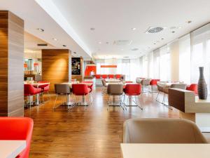 a restaurant with red chairs and tables in a room at ibis Stuttgart Airport Messe in Leinfelden-Echterdingen