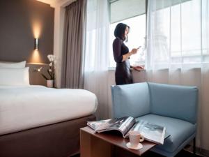 a woman standing in a hotel room looking out the window at Pullman Paris Tour Eiffel in Paris