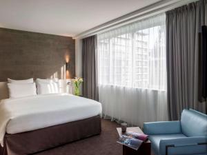 a hotel room with a large bed and a blue chair at Pullman Paris Tour Eiffel in Paris