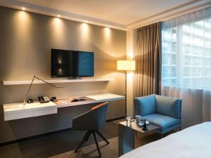 a hotel room with a desk and a tv on the wall at Pullman Paris Tour Eiffel in Paris