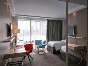 a hotel room with a bedroom with a bed and a desk at Pullman Paris Tour Eiffel in Paris