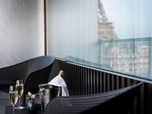 a balcony with a table with wine glasses and the eiffel tower at Pullman Paris Tour Eiffel in Paris