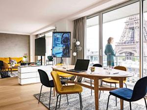 a living room with a dining room table with a laptop at Pullman Paris Tour Eiffel in Paris