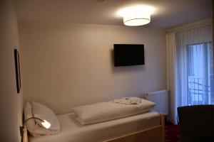 a room with a bed and a flat screen tv at Pension Seeblick in Seebruck
