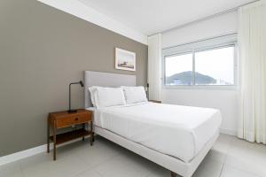 Un dormitorio blanco con una cama y una ventana. en Cannes Club by Viva - Residencial a 200m da praia Ingleses do Rio Vermelho, en Florianópolis 68 fotos más
