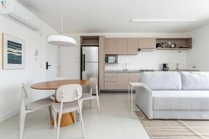 Una cocina y una sala de estar con una mesa y un sofá. en Cannes Club by Viva - Residencial a 200m da praia Ingleses do Rio Vermelho, en Florianópolis