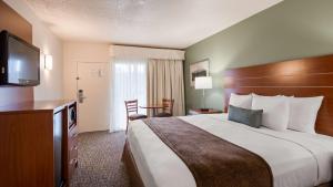 a hotel room with a bed and a flat screen tv at Best Western Buffalo Ridge Inn Near Mt Rushmore in Custer +42 photos