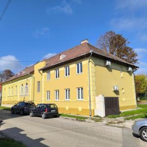a yellow house with cars parked in front of it at Deák Houses in Nagykőrös
